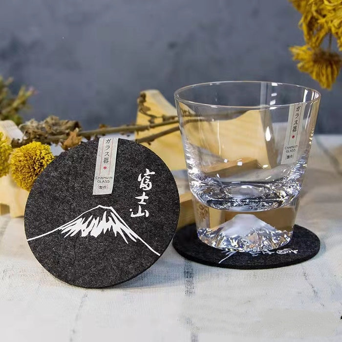 Set of eight round black felt coasters arranged on a wooden table surface.
