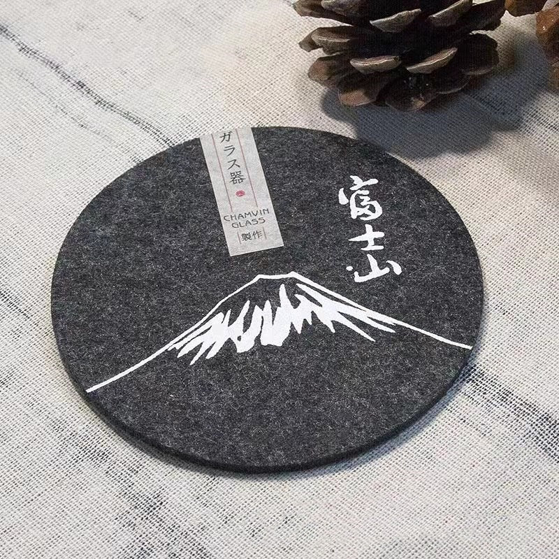 Set of eight round black felt coasters arranged on a wooden table surface.