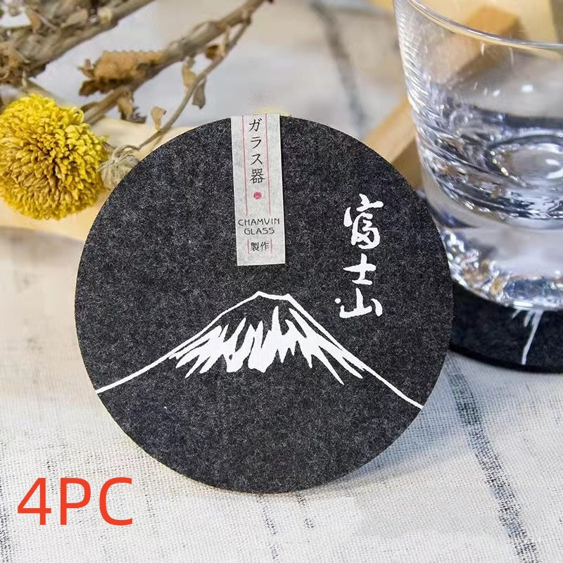 Set of eight round black felt coasters arranged on a wooden table surface.