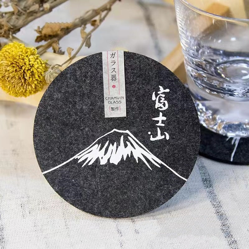 Set of eight round black felt coasters arranged on a wooden table surface.